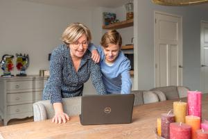 Moeder Annelies en zoon Timo kijken samen op een laptop