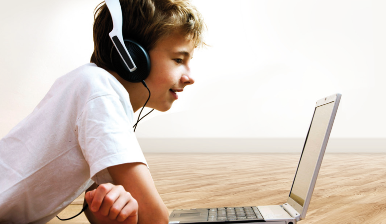 Jongen met koptelefoon kijkt naar laptop