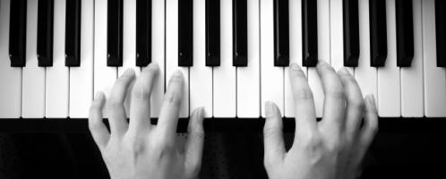 twee handen op toetsen van een piano