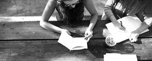 twee dames aan picknicktafel lezen en schrijven