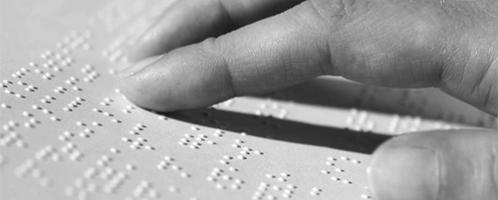 hand die over een blad met braille gaat