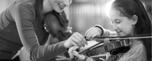 Muziekdocent helpt leerling bij het bespelen van een viool
