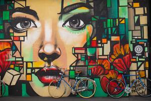 gezicht in graffitti op een muur met twee geparkeerde fietsen