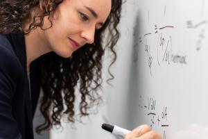 jonge vrouw schrijft wiskundige formules op een whiteboard