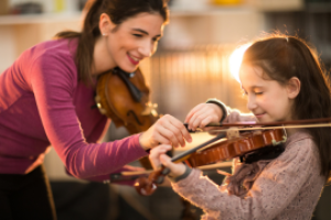 Muziekdocent helpt leerling bij het bespelen van een viool